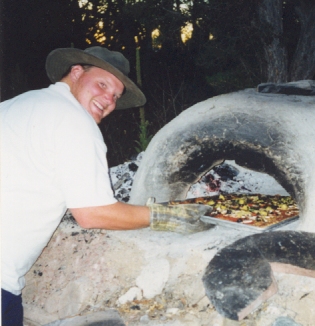 Tim cooking a pizza in a cob oven in 1999.